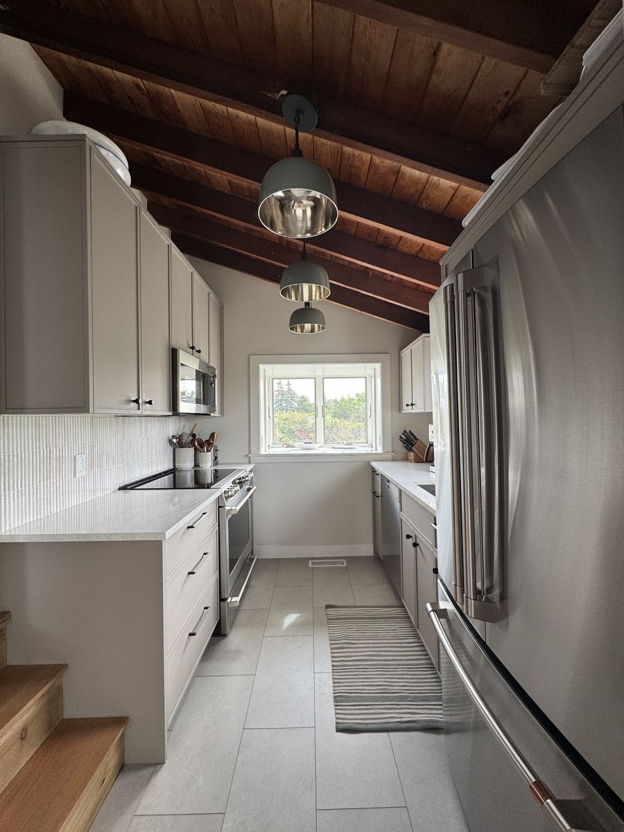 Kitchen after renovation — light galley kitchen with exposed wood ceiling