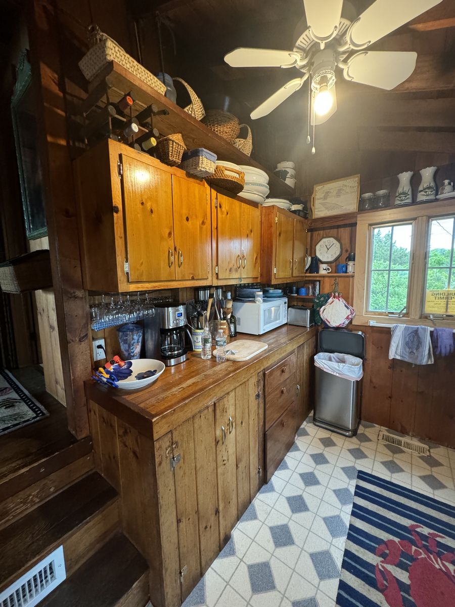 Kitchen before renovation — knotty pine cabinets and patterned tile floor