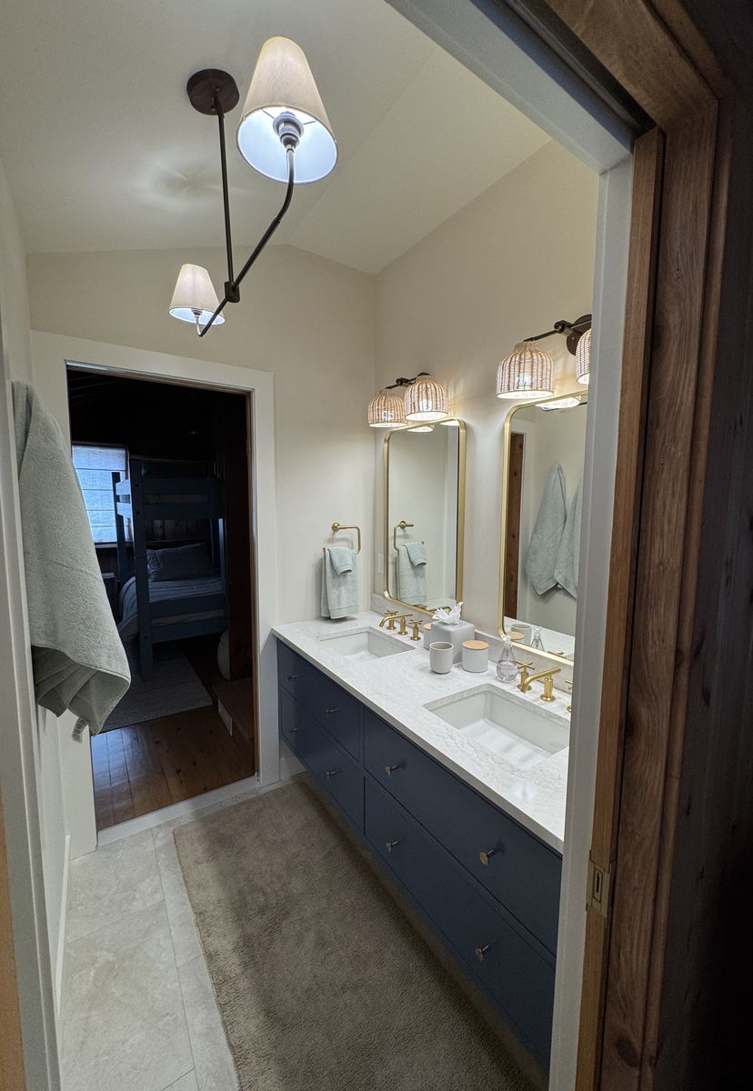 Primary bathroom after renovation — double vanity with marble counter and brass fittings
