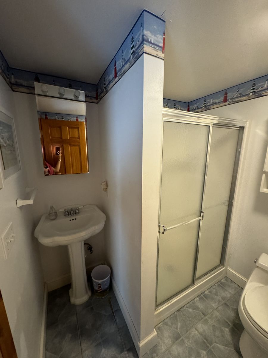 Primary bathroom before renovation — pedestal sink and enclosed shower stall