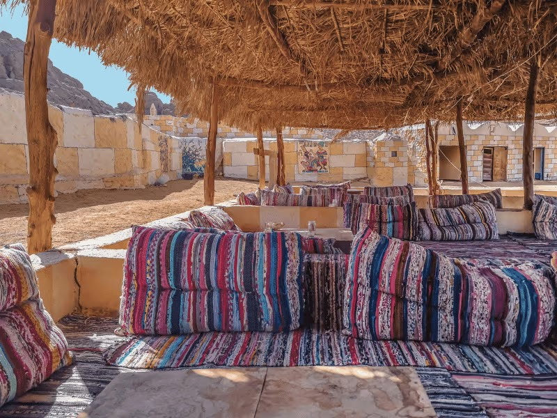 Colorful striped textiles and cushions beneath a woven canopy